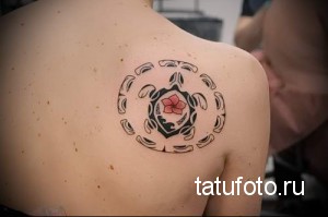 Фото тату черепахи в круге с изображением цветка. Символический рисунок татуировки в черно-белой гамме с красным цветком.