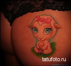 Фото тату на бедре с изображением мультяшного ягненка с розовым бантиком. Яркий и красочный рисунок татуировки в стиле мультфильм.
