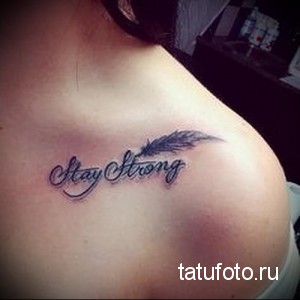 Фото тату надписи 'Stay Strong' с изображением пера. Черные чернила, каллиграфический шрифт, символизм силы и свободы. Идеально для тех, кто стремится к преодолению трудностей.