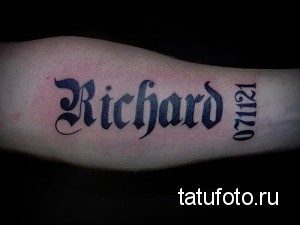 Фото тату имени 'Richard' и даты '071121', выполненного в готическом стиле черными чернилами на предплечье.