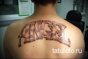 Черно-белая татуировка надписи 'Angel' на спине, выполненная в простом шрифте.