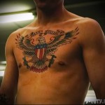 Фото тату на груди с изображением белоголового орла, держащего американский флаг и скрещенные пистолеты. Яркие цвета и детализированная проработка.