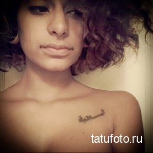 Фото татуировки на плече с арабской каллиграфией. Рисунок татуировки выполнен черными чернилами, с акцентом на изящные линии.