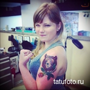 Фото тату на руке, изображающее голову медведя с розой. Нежный и милый рисунок татуировки в ярких цветах.