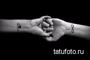 Фото парных тату: на запястьях двух людей изображены символы бесконечности, соединенные рукопожатием.