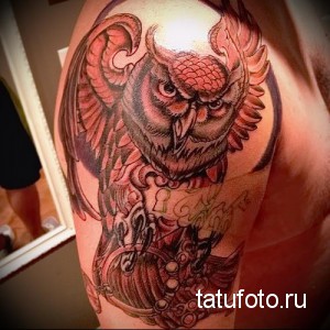 Фото тату реалистичной совы на плече, выполненной в черно-серых тонах. Рисунок отличается высокой детализацией и проработкой перьев.