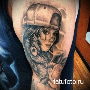 Фото тату на предплечье: девушка в кепке с ярким макияжем в стиле клоуна, выполненная в реалистичной технике с использованием черных и серых оттенков.