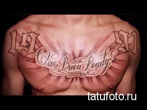 Фото тату с цифрами 1991 и надписью "Was Born Ready" на груди. Черно-серый рисунок с стилизованным шрифтом и лучами света.