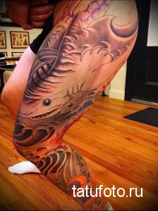 Фото тату: реалистичная татуировка акулы и волны в японском стиле на ноге, выполненная в черных и красных тонах.