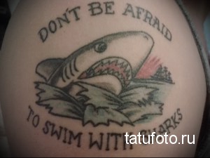 Фото тату: татуировка акулы с надписью "Don't be afraid to swim with sharks" на боку. Мотивационный рисунок татуировки в стиле олд скул.