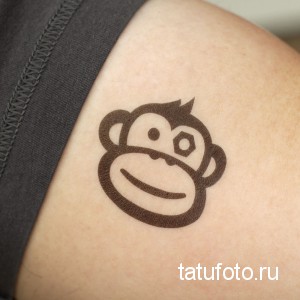Фото тату на плече: простая татуировка с изображением головы обезьяны, выполненная в черном цвете.