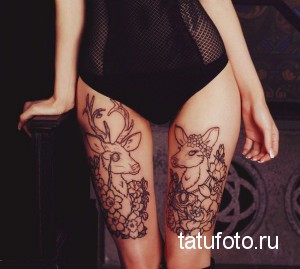 Фото тату двух оленей с рогами, украшенными цветами, на бедрах девушки. Черно-белый рисунок с тонкими линиями и детальной проработкой.