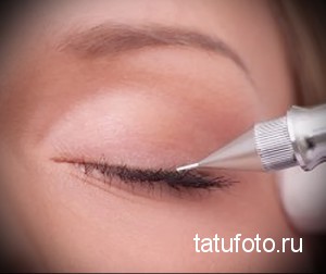 Крупный план процесса татуажа век. Виден аппарат для татуажа и рука мастера, аккуратно прорисовывающая тонкую линию вдоль линии роста ресниц.