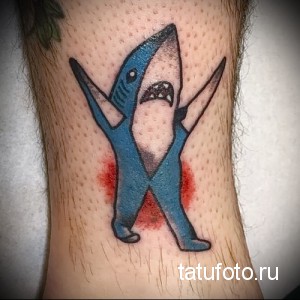 Фото тату мультяшной акулы, стоящей на ногах, в стиле олдскул с красными пятнами, расположенной на ноге.