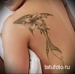 Фото тату с изображением цветов и растительных узоров на плече женщины. Рисунок выполнен в нежных тонах и имеет изящную форму.