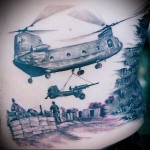 Фото тату на руке с изображением вертолета CH-47 Chinook в зоне боевых действий, с солдатами и техникой. Реалистичный рисунок татуировки.