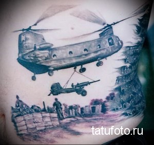 Фото тату на руке с изображением вертолета CH-47 Chinook в зоне боевых действий, с солдатами и техникой. Реалистичный рисунок татуировки.