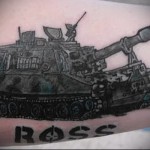 Фото тату на руке с изображением танка и надписью "ROSS". Черно-серый рисунок, реалистичный стиль.