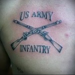 Фото тату с изображением перекрещенных винтовок и надписи 'US ARMY' и 'INFANTRY' на груди. Черно-серая татуировка в классическом стиле.