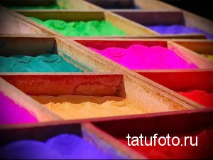 Фотография палитры порошковых пигментов для татуировок, разложенных в секциях. Видны яркие цвета: розовый, красный, желтый, зеленый, синий и фиолетовый.