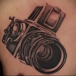 Фото тату на груди с изображением старинного пленочного фотоаппарата. Черно-белое исполнение, реалистичная детализация и тени.