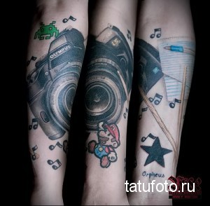Фото тату на руке, изображающее различные винтажные фотоаппараты, ноты и элементы ретро-стиля. Черно-белое исполнение с детальной проработкой.