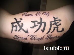 Фото тату: китайские иероглифы и английский текст "Success Is Only Obtained Through Happiness" на предплечье. Рисунок татуировки выполнен в черных тонах.