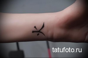 Фото тату на запястье: маленький черный иероглиф, выполненный в минималистичном стиле. Идеально для тех, кто ценит лаконичность.