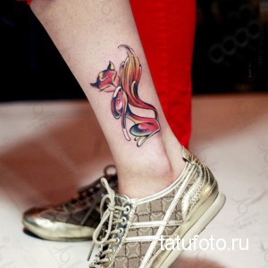 Фото тату лисы на лодыжке. Яркий рисунок с использованием красных, оранжевых и желтых цветов. Татуировка с элементами сказочного стиля.