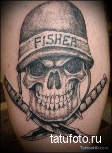 Фото тату черепа в военной каске с надписью 'FISHER' и перекрещенными кинжалами на руке. Черно-серая татуировка в реалистичном стиле.