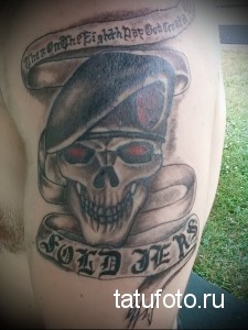 Фото тату черепа в берете с красными глазами и надписью "Then On The Eighth Day God Created Soldiers". Черно-серые тона, реалистичный стиль.