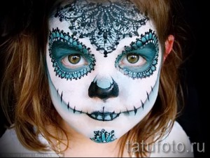 Фото тату-макияжа на лице девушки в стиле День мертвых (Dia de los Muertos) с изображением черепа и цветочных узоров.