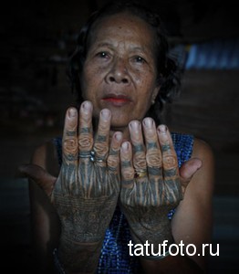 Фотография пожилой женщины с татуировками на руках, демонстрирующей традиционные узоры.