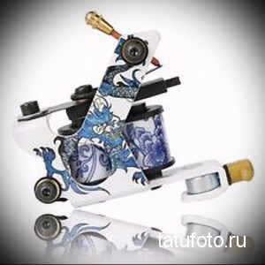 Фото тату-машинки, украшенной ярким рисунком синего дракона. Машинка выполнена в белом цвете и имеет стильный дизайн.