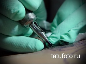 Фото процесса нанесения татуировки: игла тату-машинки касается кожи. Крупный план работы мастера.