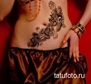 Фото росписи хной на животе: изящный узор, выполненный хной на животе женщины, украшенный бижутерией.