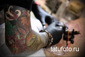 Фотография японской татуировки в стиле ирэдзуми на руке: карпы кои, цветы, волны и другие традиционные элементы.
