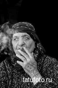 Фото тату: Руки пожилой женщины с татуировками, курящей сигарету. Черно-белое изображение, реалистичный портрет, следы времени.