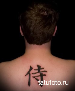 Фото татуировки на затылке, представляющей собой один иероглиф. Татуировка выполнена черным цветом и выглядит минималистично.
