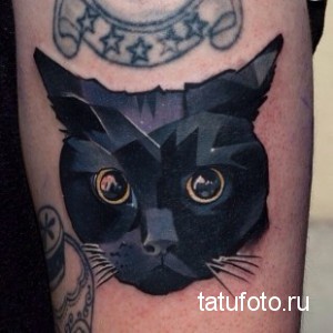Фото тату полигонального черного кота на руке. Яркий рисунок татуировки с использованием различных оттенков серого и желтых глаз.