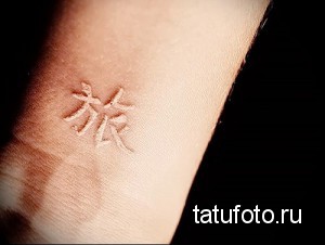 Фото тату: небольшой белый иероглиф, расположенный на запястье, выполненный в минималистичном и изящном стиле.