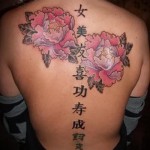 Тату с иероглифами на спине и двумя розовыми цветами
