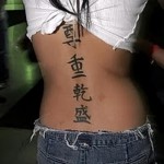 Тату с крупными иероглифами на спине молодой азиатки в короткой юбке