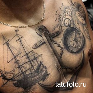 Фото тату: большая татуировка на груди мужчины с изображением якоря, парусника, компаса и старинных документов. Черно-белый рисунок в реалистичном стиле.