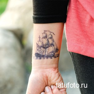Фото тату: изящный черно-белый парусник на запястье. Детализированный рисунок с волнами и надписью.