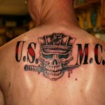 Фото тату на спине: изображение черепа в военной каске USMC с двумя скрещенными кинжалами и надписью 'U.S.M.C.' в черно-красных тонах.