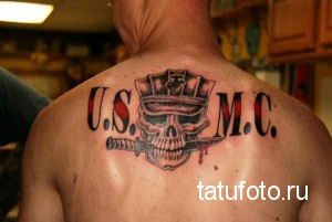 Фото тату на спине: изображение черепа в военной каске USMC с двумя скрещенными кинжалами и надписью 'U.S.M.C.' в черно-красных тонах.