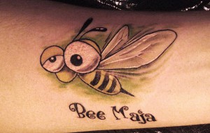 Фото милой мультяшной татуировки пчелы с большими глазами и надписью 'Bee Maja' на руке.