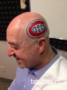 Фото татуировки с логотипом хоккейной команды Montreal Canadiens на лысой голове. Логотип выполнен в красном, синем и белом цветах.
