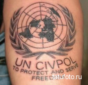 Фото тату на руке с изображением эмблемы Организации Объединенных Наций. Рисунок выполнен в черно-белом стиле с использованием теней и контуров.